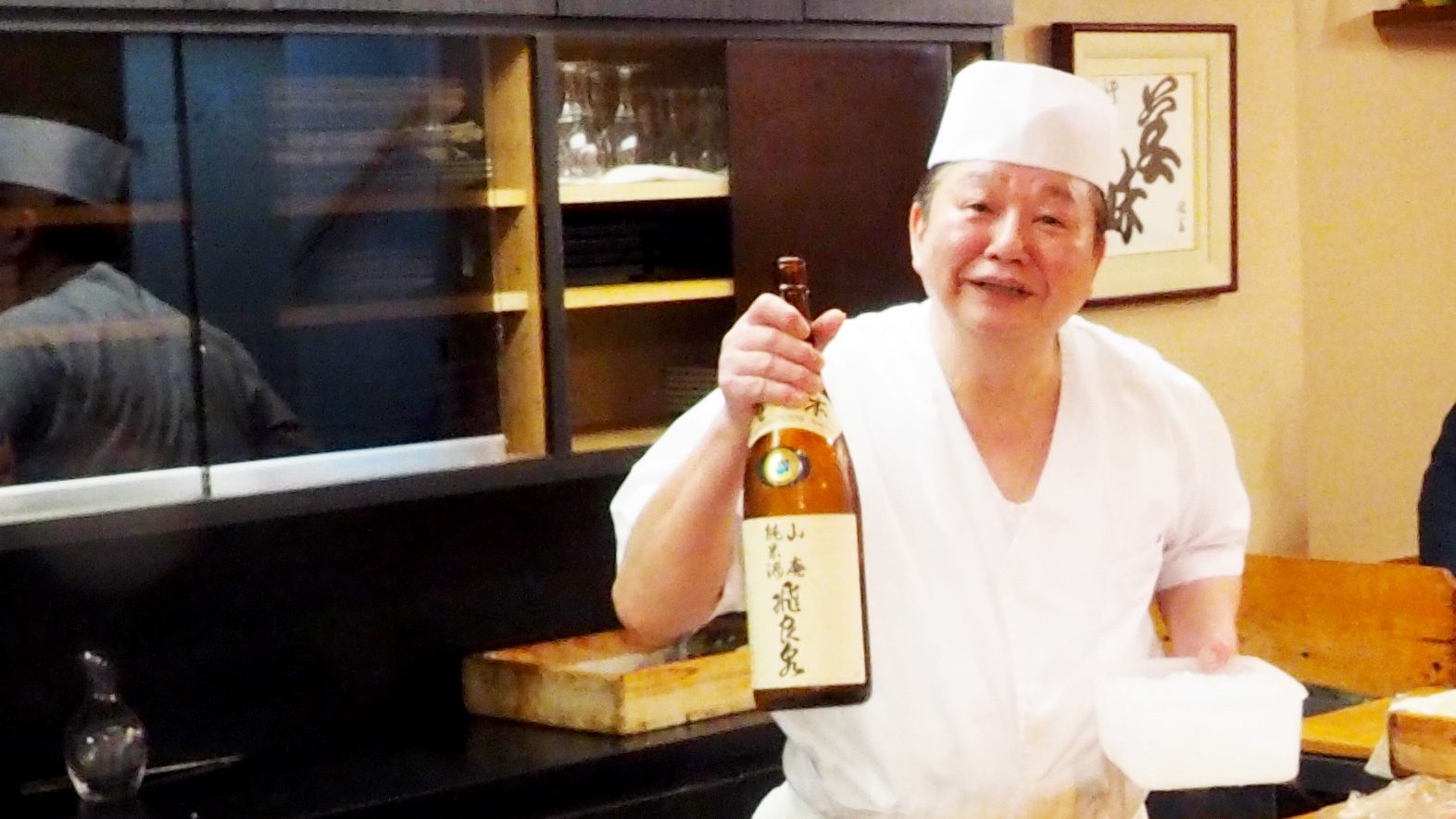 Sushi chef at Sushi Yajima holding a bottle.